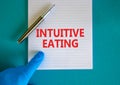 Intuitive eating symbol. White note with words Intuitive eating, beautiful blue background, doctor hand and metallic pen. Medical