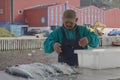 Inuit eskimo man preparing fresh fish on a market in Qaqortoq Greenland