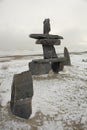 Inukshuk on Edge of Cloudy, Snowy Hudson Bay