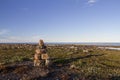 Inukshuk or Inuksuk on a rocky tundra with water in the background in late June