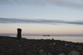 Inuksuk along arctic shore with barge in background