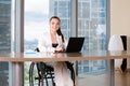 Invalid or disabled young business woman person sitting wheelchair working in office on a laptop Royalty Free Stock Photo