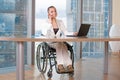 Invalid or disabled young business woman person sitting wheelchair working in office on a laptop Royalty Free Stock Photo