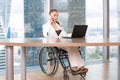 Invalid or disabled young business woman person sitting wheelchair working in office on a laptop Royalty Free Stock Photo