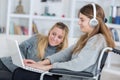 Invalid girl on wheelchair with laptop with friend Royalty Free Stock Photo