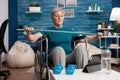 Invalid senior woman exercising arm muscle resistance using elastic band watching fitness video