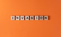 Invasion word phrase in wooden letters. Motivation and slogan. Orange background