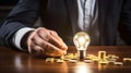 Inventive Inspiration: Hand Grasping Light Bulb Above Coins on Desk Royalty Free Stock Photo