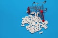 Inverted trolley with purchased medicines, scattered pills on a blue background, medical concept Royalty Free Stock Photo