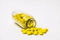 Inverted glass vial with scattered small yellow pills Royalty Free Stock Photo