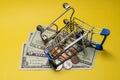 An inverted metal shopping trolley lies on small US bills and coins. The concept of online purchases and sales, unsuccessful Royalty Free Stock Photo