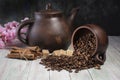 An inverted mug with coffee beans on the background of a clay teapot, sugar cubes,cinnamon sticks and cherry blossoms on a wooden Royalty Free Stock Photo