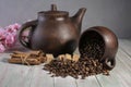 An inverted mug with coffee beans on the background of a clay teapot, sugar cubes,cinnamon sticks and cherry blossoms on a wooden Royalty Free Stock Photo