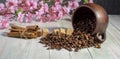 An inverted mug with coffee beans, sugar cubes, cinnamon sticks and cherry blossoms on a wooden table Royalty Free Stock Photo