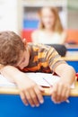 Invest in good vitamin supplements to help them do their best. Young boy lying with his arms over his desk, asleep in Royalty Free Stock Photo