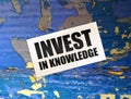 Invest in Knowledge words on card on wooden table. Business education concept