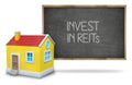 Invest in reits text on blackboard with 3d house Royalty Free Stock Photo