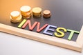 Invest text on blackboard with coin and light Royalty Free Stock Photo