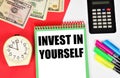 Invest in yourself. The inscription in the notebook on the background of the clock.