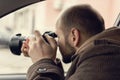 Investigator or private detective or reporter or paparazzi sitting in car and taking photo with professional camera Royalty Free Stock Photo