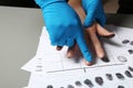 Investigator taking fingerprints of suspect on table