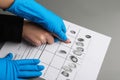 Investigator taking fingerprints of suspect at table, closeup