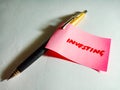 investing text displayed on green colour paper slip with pen concept Royalty Free Stock Photo