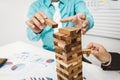 Business man and woman stop wood tower building for tumbledown.