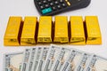 Gold bars / bullion on a pile of US dollar cash banknotes with calculator Royalty Free Stock Photo