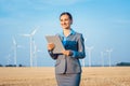 Investor in wind turbines with computer evaluating her investment on site