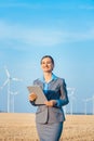 Investor in wind turbines with computer evaluating her investment on site