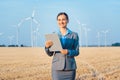 Investor in wind turbines with computer evaluating her investment on site