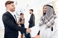 A man in arabian clothes and a man in a business suit are shaking hands. Royalty Free Stock Photo