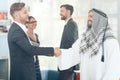 A man in arabian clothes and a man in a business suit are shaking hands. Royalty Free Stock Photo