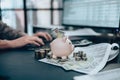 Investors hand typing keyboard, money, piggy bank on the table. Business saving money and financial concept