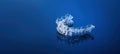 Invisible orthodontics cosmetic brackets on blue gradient background, tooth aligners, plastic braces. A way to have a beautiful