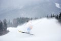 Invisible skier skiing and jumping high up in deep snow powder. Dark wooded mountains view in snowfall on background. Royalty Free Stock Photo