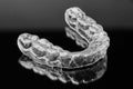 Invisible transparent dental removable braces on the black background. Orthodontic appliance for dental correction