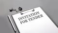INVITATION FOR TENDER text on the white paper sheet on the black background
