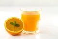 An inviting glass full of orange juice and a half one with a fresh mint leaf in its center on white background
