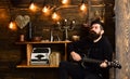 Involved in relaxation. Man bearded musician enjoy evening with bass guitar, wooden background. Man with beard holds Royalty Free Stock Photo