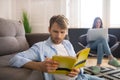 Involved young man studying before exam, his wife sitting behind him