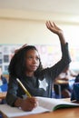 Involvement is important from an early age. a young girl sitting in her school classroom and raising her hand to answer Royalty Free Stock Photo