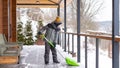 Involving children in housework concept. The boy cleans the snow on the terrace of his house with a big shovel.  Little helpers Royalty Free Stock Photo