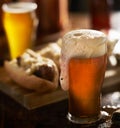 IPA beer with overflowing foamy head in mug served with bratwursts Royalty Free Stock Photo