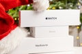 Iphone, Apple watch, Macbook Air boxes with Santa Claus hat and Christmas tree on the background Royalty Free Stock Photo