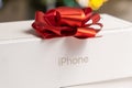 Iphone box with a red bow against blurred backround. Royalty Free Stock Photo