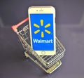 IPhone with Walmart logo in mini shopping cart on table