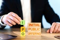ipo concept. a man stacks wooden blocks with the words Initial, Public, Offering. Royalty Free Stock Photo