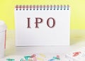 IPO the word is written on a blank sheet in a notebook standing on a table on a yellow background